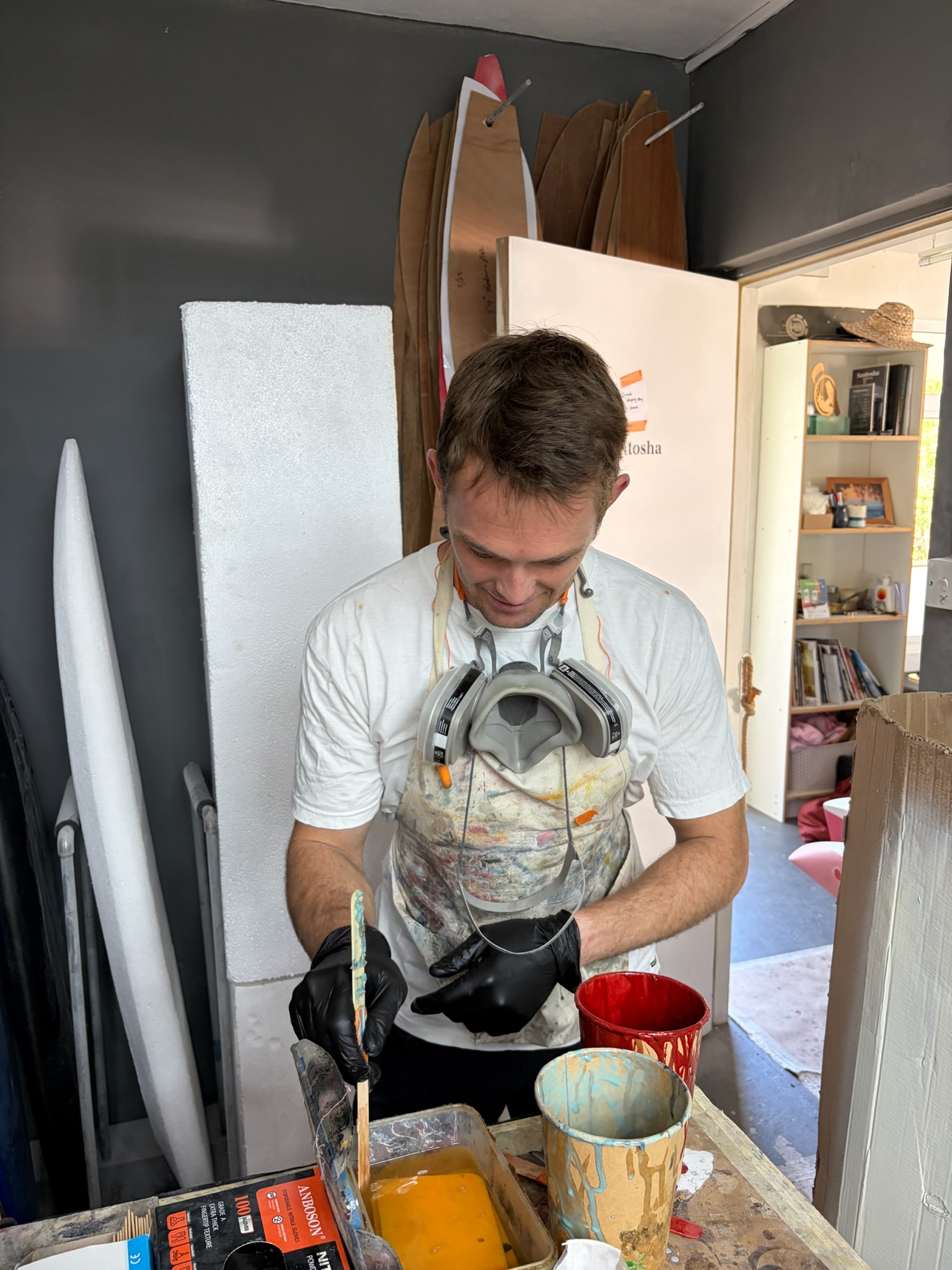 A shaper mixing resin in the Santosha bay, respirator around his neck