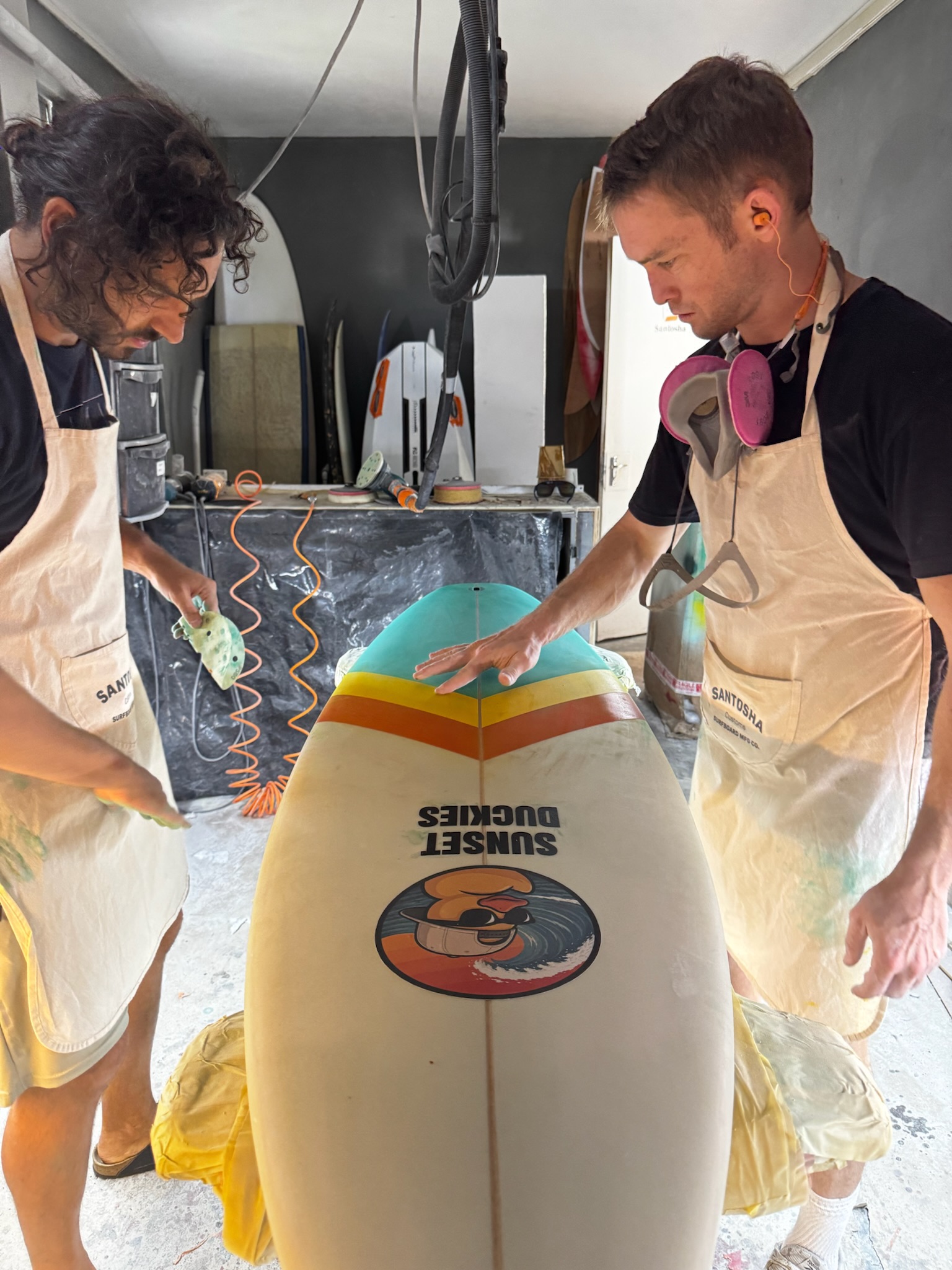 The two Santosha shapers running their hands over the finished board, nose up