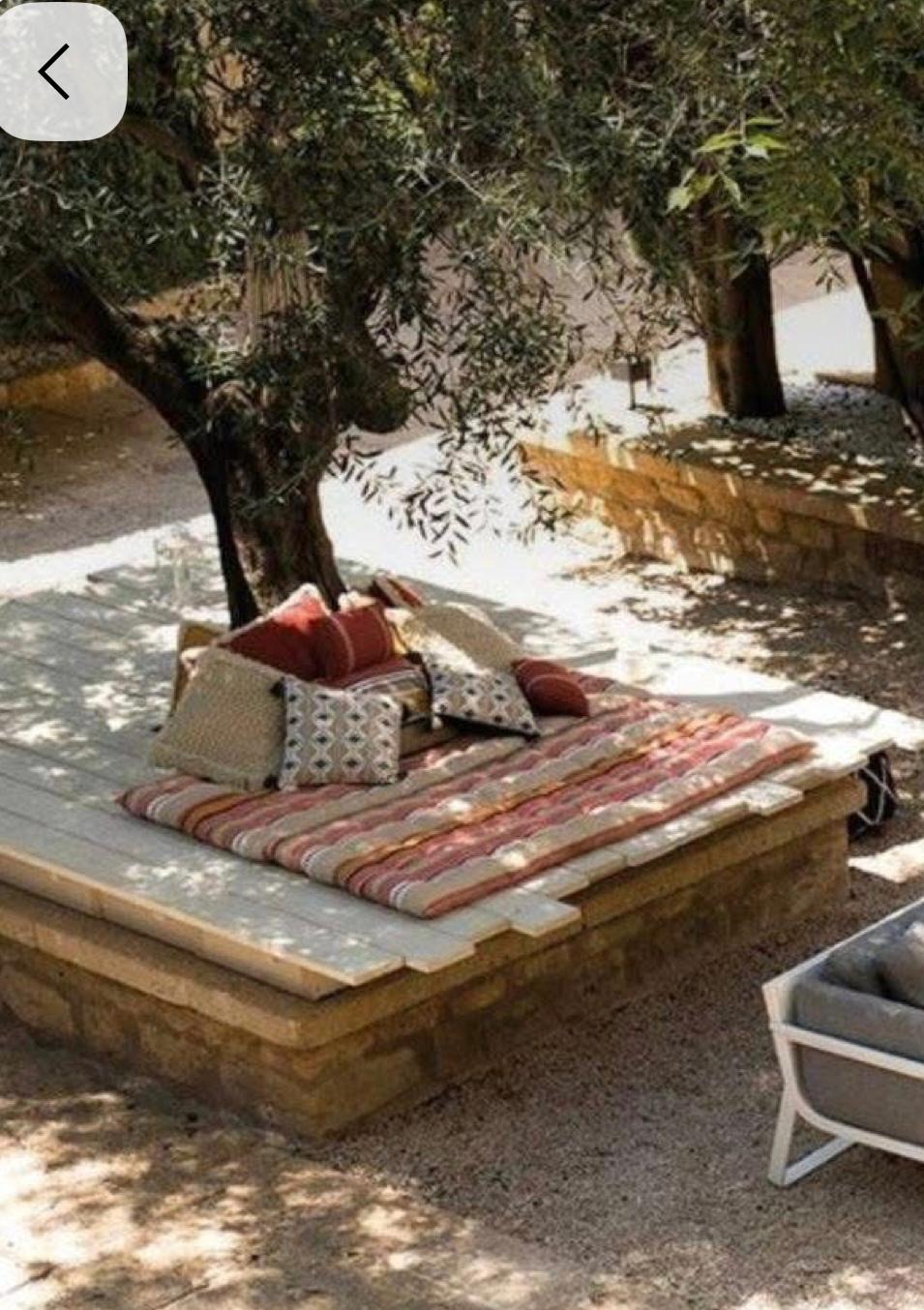 Wide view of stone daybed platforms under trees