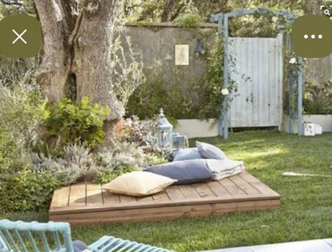 Wooden deck platform with cushions under a tree