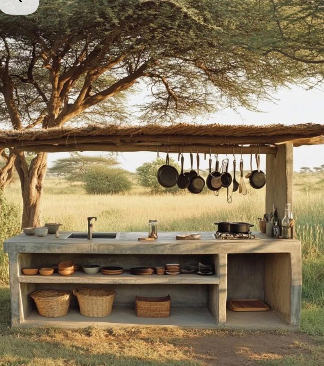 Open-air kitchen with hanging pans and thatched roof