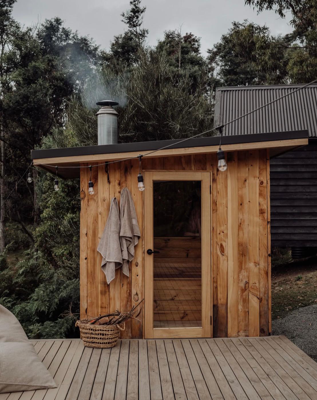 Wooden sauna hut with string lights on a deck